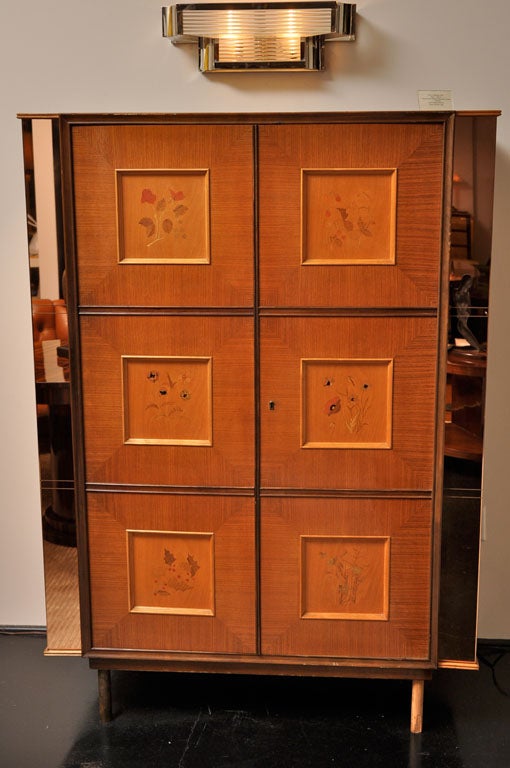 Pair of armoires in fruitwood with 6 detailed marquetry flower panels on each piece. Copper-toned mirrored edges frame the sides of the cabinets with etched squares alluding to the panels on the facade. Citron wood interiors with drawers and