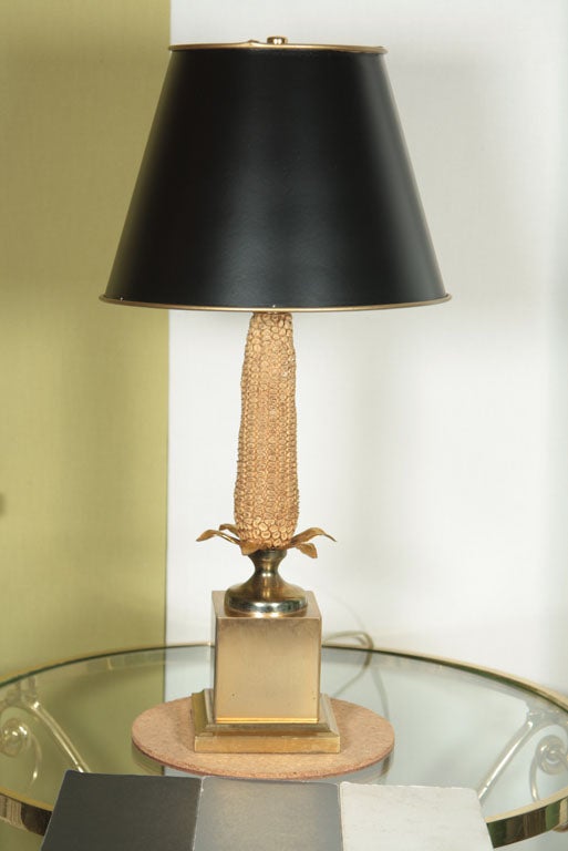 A PETRIFIED EAR OF CORN SITS ON A BRASS BASE AND IS ADORNED BY BRASS LEAVES