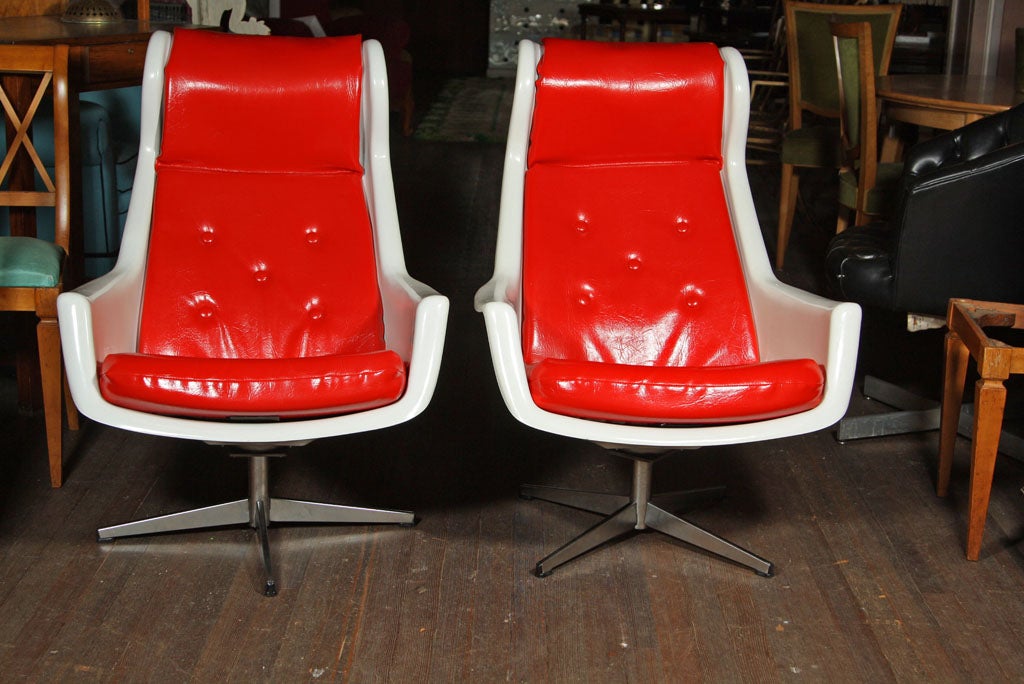 A steel swivel based molded chair upholstered in red vinyl. Seat height is 18