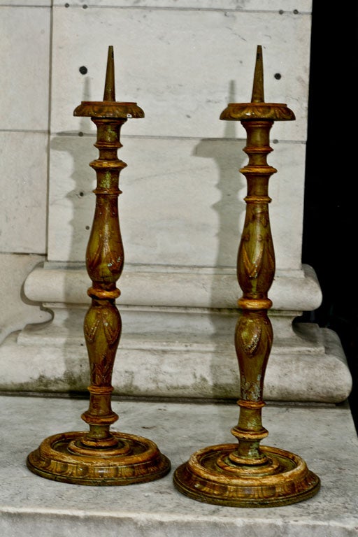 This large and decorative  pair of pricket sticks are from the later part of the 19th century. The paint decoration is unusual for candle sticks of this kind and consists of draped swags on the baluster shaped middle section with large egg and dart