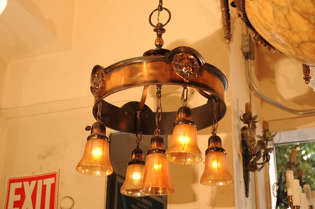 Very elegant and simple ring style fixture with great original flash copper finish over bronze. The ring is accented with cast faces of babies. Hanging from the fixture are five original period carnival glass shades with a larger center shade.