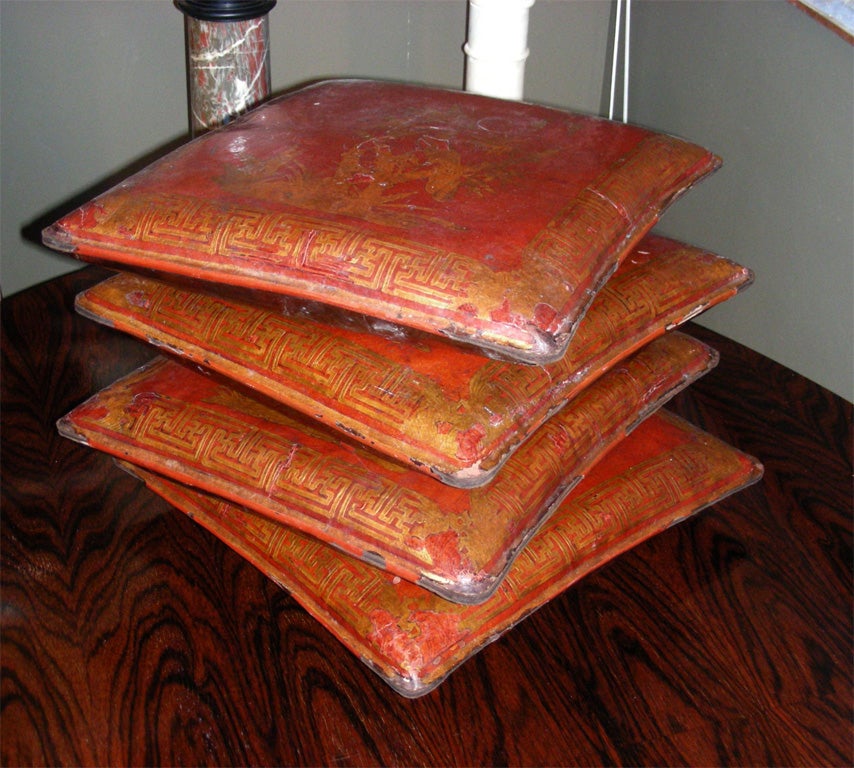 Four end of 19th century Chinese leather pillows, engraved, painted and lacquered in red. Stuffed with horse-hair. Four different decorative motifs.