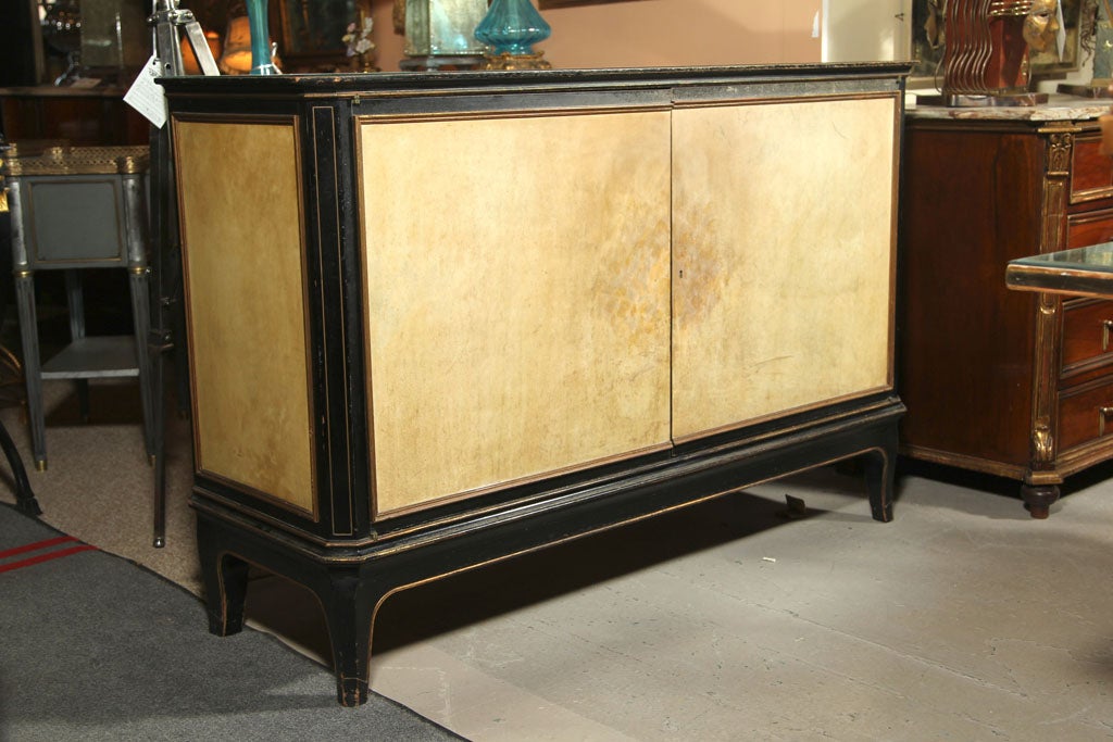 One of a Kind, Stamped Jansen sideboard. the top, front and sides of parchment veneer framed in ebonized wood with gilt gold high- lights. Glass Top. The interior of shelf design.