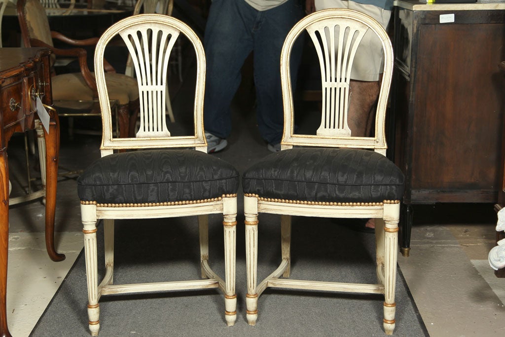 Group of 8 Gustavian Style Dining Chairs. White distress paint decorated with gilt gold high lights. Louis XVI Style legs leading to a comfortable plush set. The set having new fabric and tacked down design. The back of balloon form. Study. CAN BUY