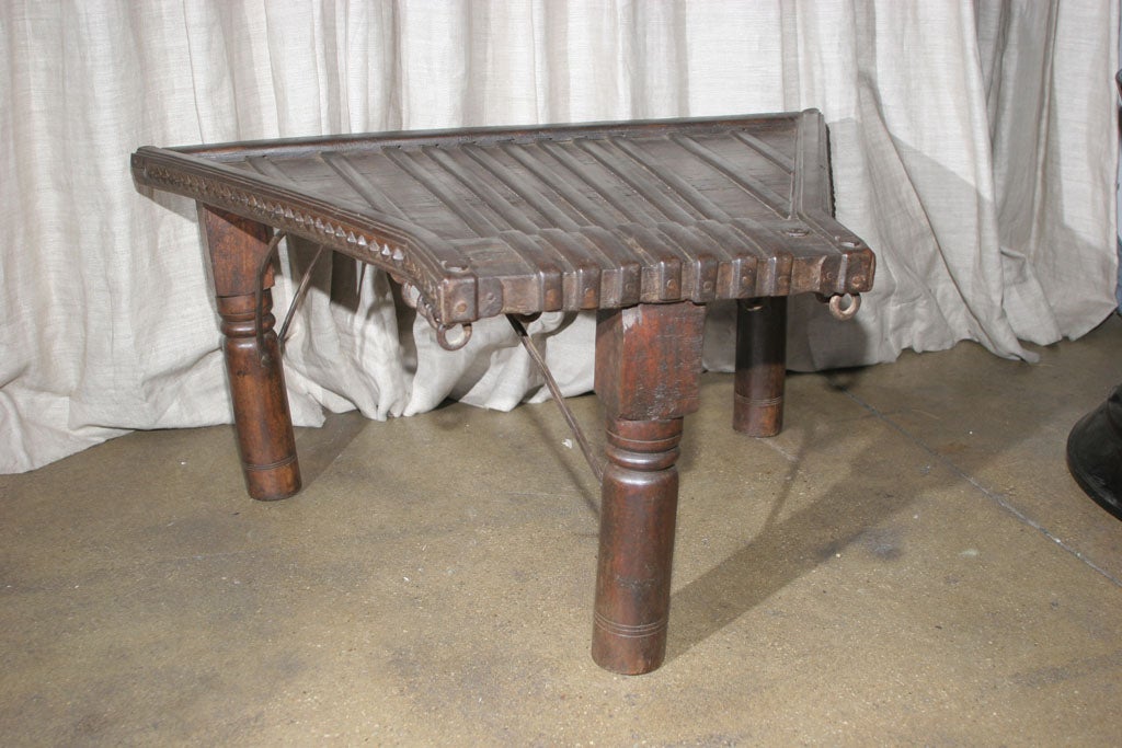 An angular ox cart seat table decoratied with a studded border and metallic hoops.