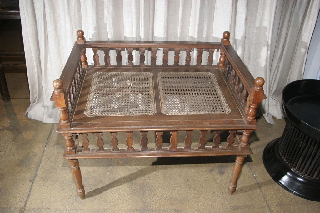A teakwood table with decorative crib border and two cane panel insets