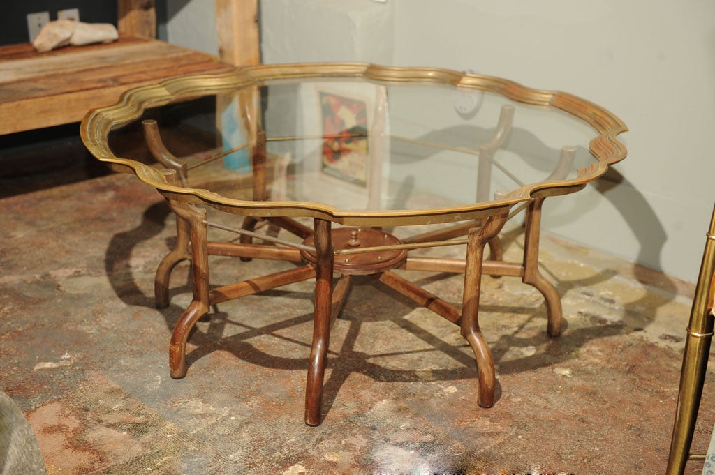 Original Glass top trimmed with solid un-lacquered brass edge detail that's reminiscent of India, the top is absolutely magnificent. Wood base with brass stretchers is in line with a nautical them. This table gets so much attention in the shop, we