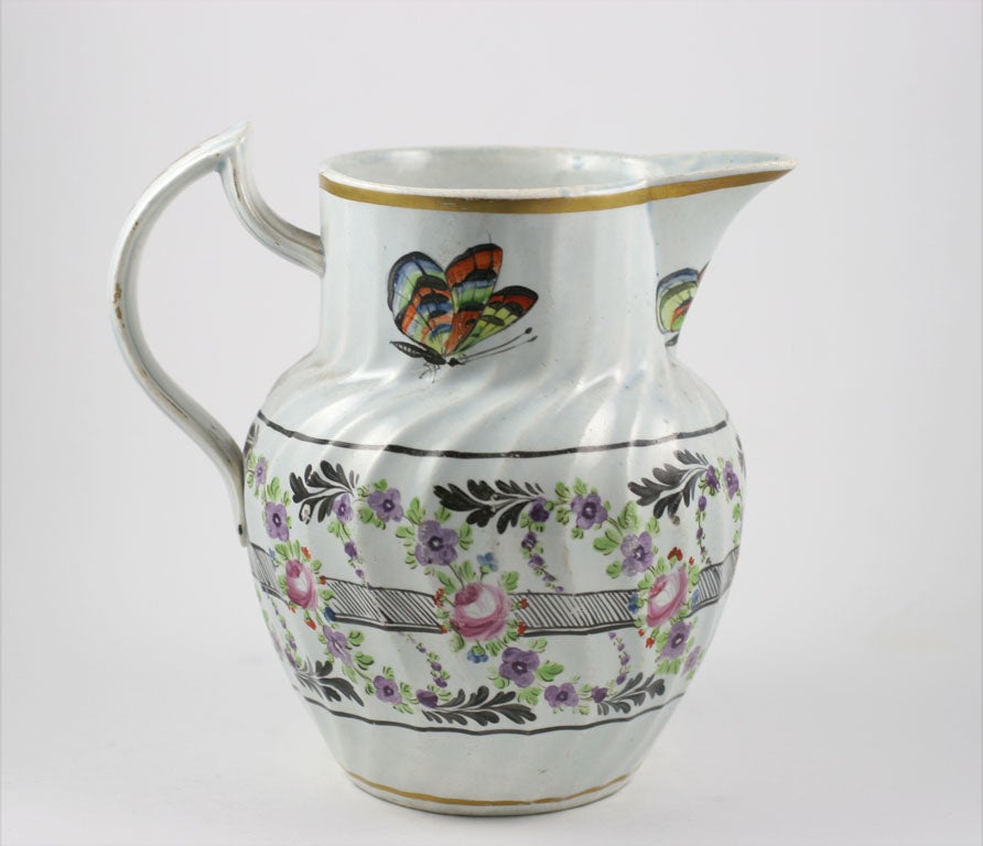 A rare signed Leeds Pottery pearlware pitcher painted with flowers and butterflies and a saying in gilt, dated 1804
