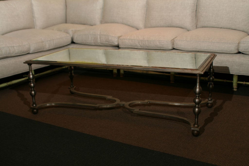 A French wrought iron turned baluster and X-form stretcher base with antiqued mirror top coffee table.