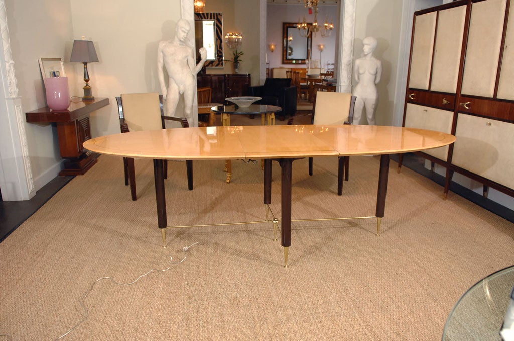 French brass mounted sycamore and mahogany dining table on legs joined by a brass stretcher, attributed to Batistin Spade