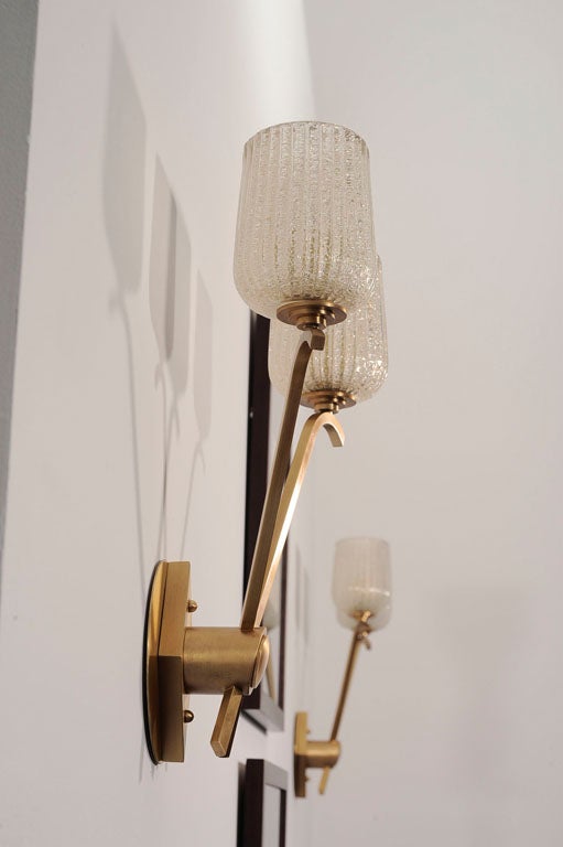 Pair of two-arm sconces by Jules Leleu (1883-1961)<br />
Gilt-bronze with original gold dust Murano shades