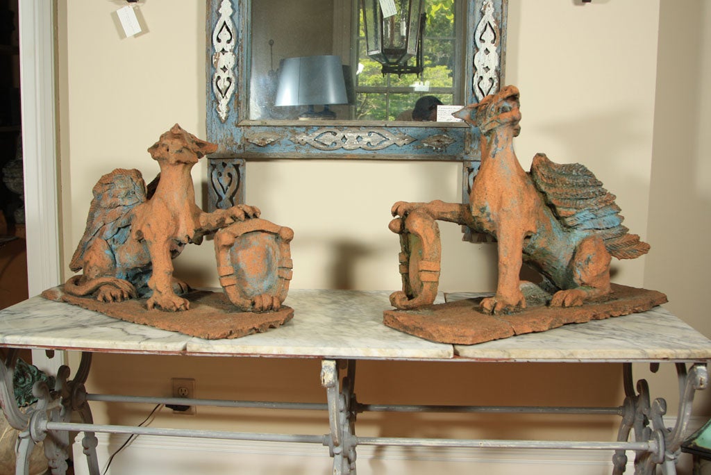 Superlative in all respects, this proper opposing pair of French hand-modeled terracotta armorial griffins has traces of blue paint and is signed 