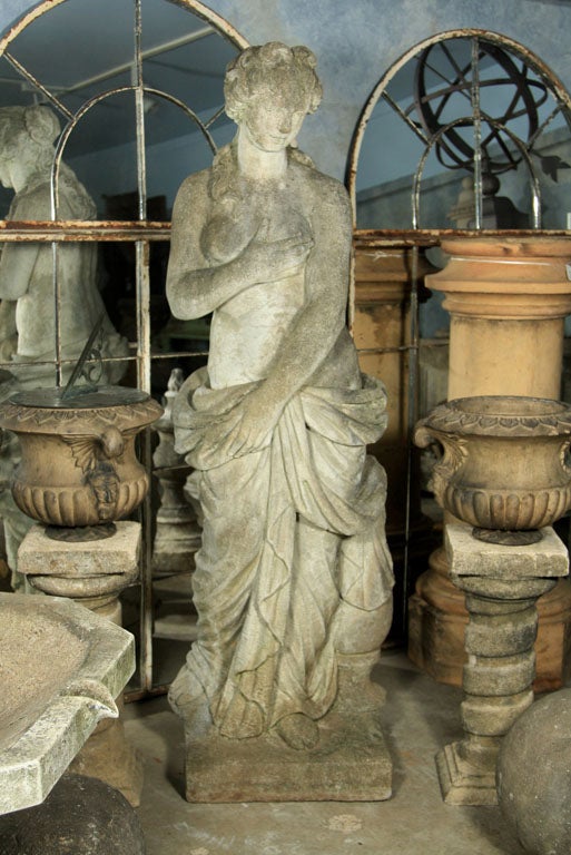 This lovely, classical and life-sized cast stone statue of Venus undressing for the bath is beautifully-weathered and would be the perfect centerpiece in any garden.  A comely face, well-modeled body, gracefully draped robe and charming pose combine
