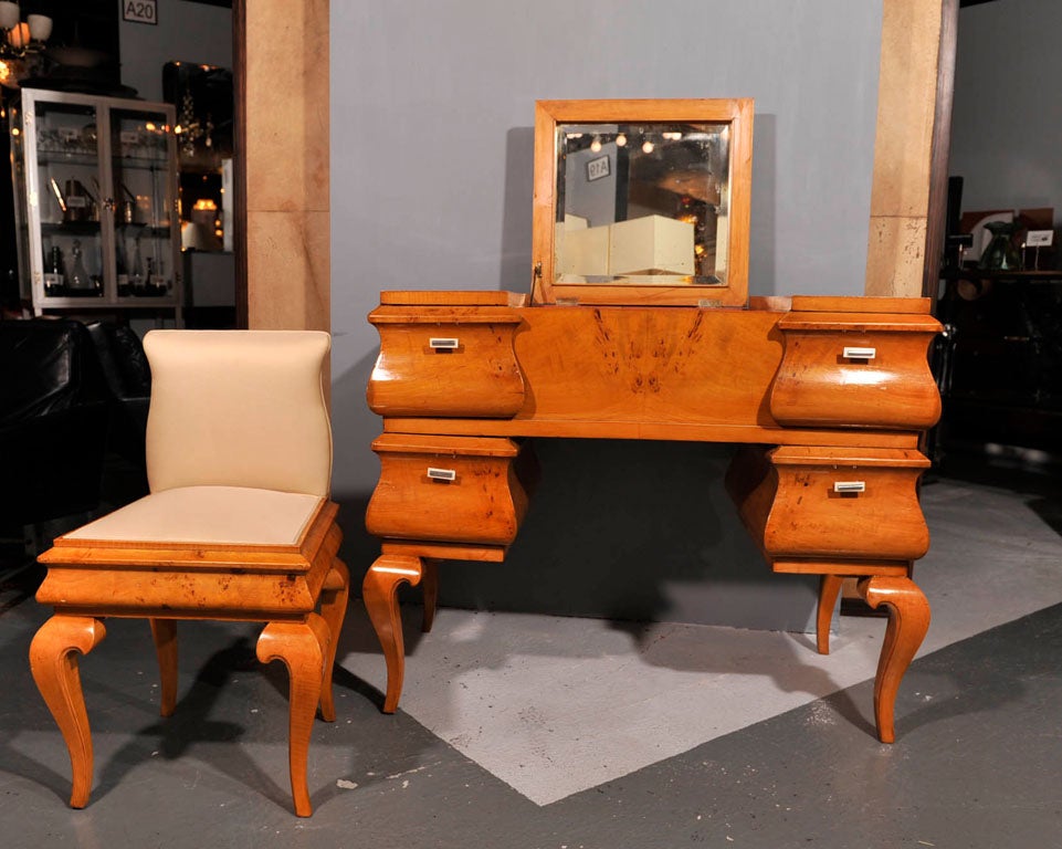 Exceptional Biedermeir inspired vanity and chair in book matched Poplar. Vanity has 4 drawers with bakelite and nickel pulls and a flip up mirror. Back is also finished. Chair features new champagne color silk upholstery. Could also be used as a