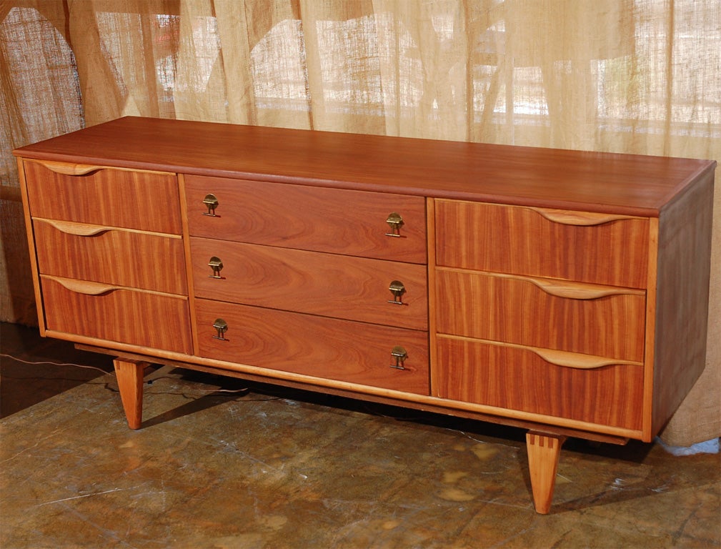 Custom made 9 drawer dresser with brass toggle pulls. The dresser is primarily made of teak, with quarter sawn drawer fronts with sculpted oak handles on the outer drawers. The legs are tongue and groove oak with teak detail for contrast.