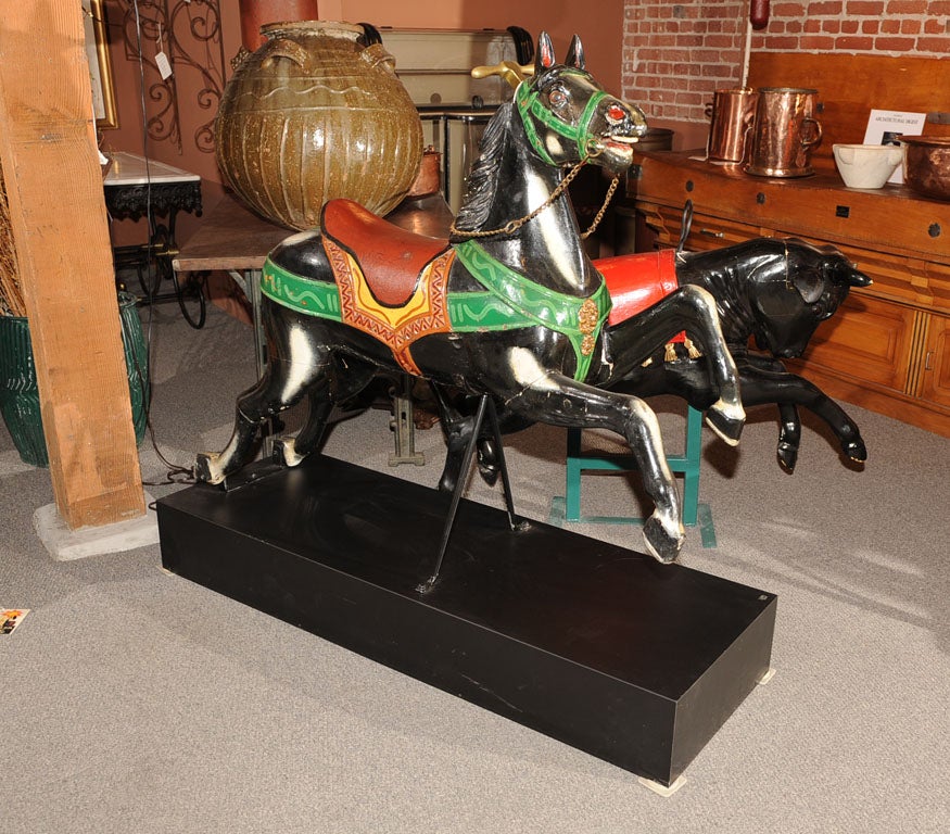 Unique & exceptional hand carved and painted galloping carousel horse, expressive face with glass eyes &  brass handle, bit chain and front medallions.
Mounted on painted plinth,
Late 19th century, France