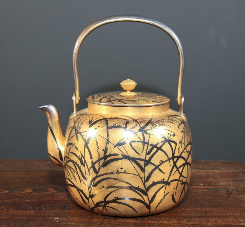 Japanese gilded silver water kettle. The body of the kettle constructed with layered silver sheets the inside with slightly raised pattern of summer grasses. The exterior with gilded surface and black lacquer (with some losses) pattern that matches