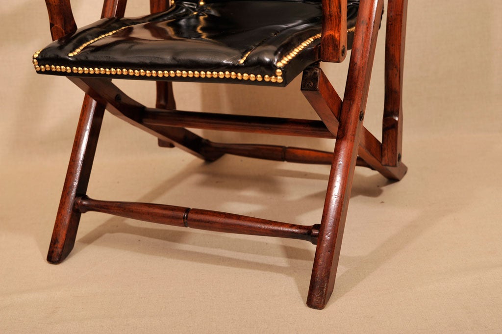Folding Mahogany and Black Leather Campaign Chair with Brass Nail Head Detailing. England, Late 19th Century.<br />
<br />
23.5 inches wide x 41.5 inches high