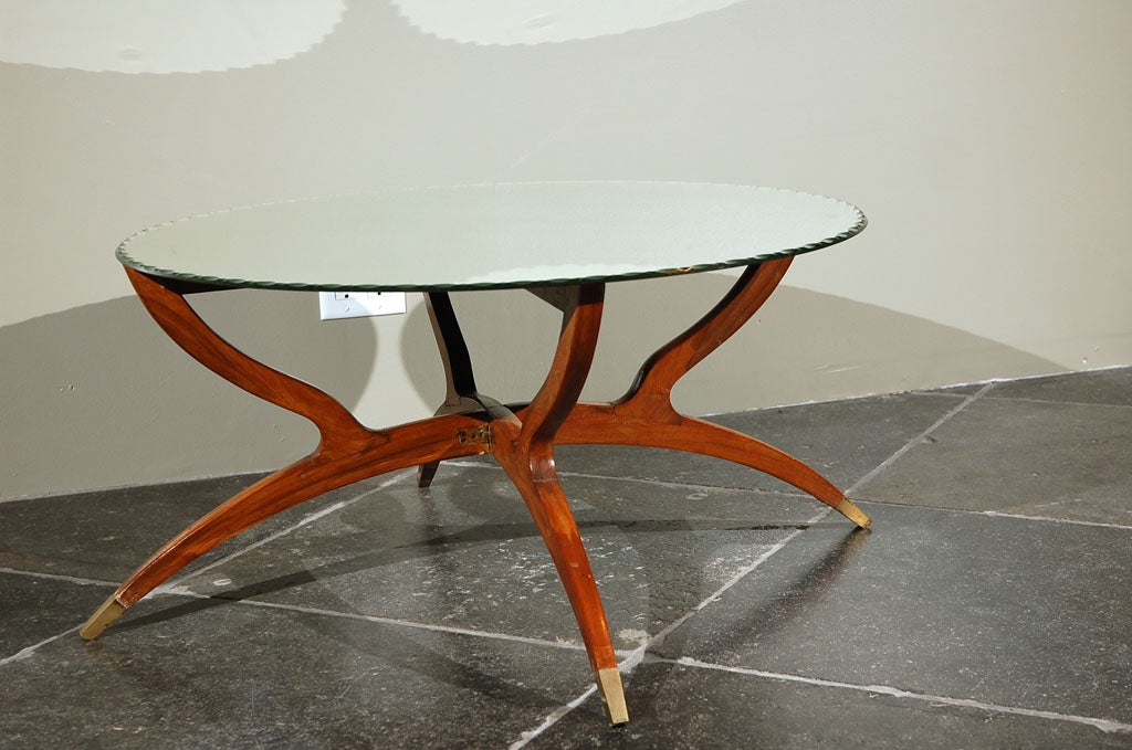 Italian Design 1950 <br />
In the style of Gio Ponti<br />
Folding coffee table in exotic wood with four legs ended with gilt bronze casters, beveled mirror top. <br />
Round top in mirror. <br />
<br />
Diam: 31