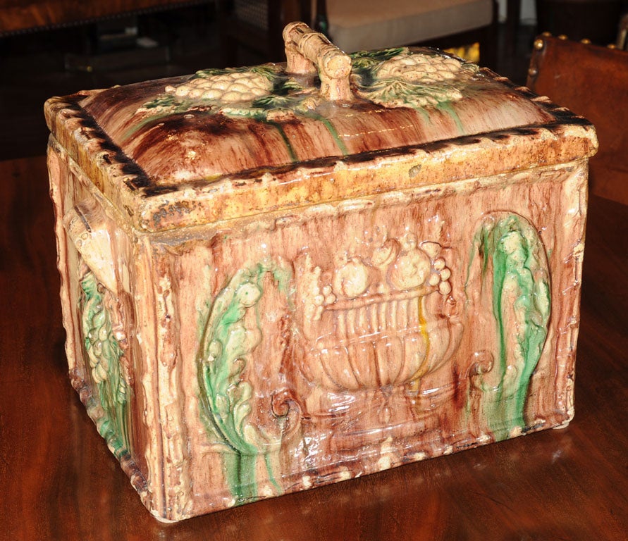 A Majolica treacle-glazed bread box from Scotland featuring two sides with an opposing relief of a fruit-laden urn between scrolls adjacent to two sides with an opposing relief of grape clusters below moulded handles. A fitted lid featuring a