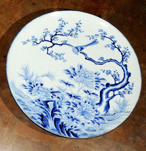 A large 19th c. blue and white Imari charger featuring a design of a bird in a blossoming plum tree (prunus) above a bed of chrysanthemums or peonies. <br />
From Arita, Saga Prefecture, Japan.