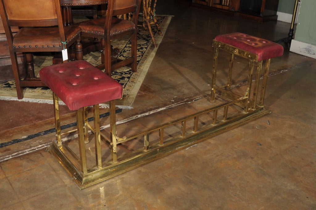 A superb quality English club fender of brass featuring two opposing tufted leather pad seats above a railed front and curb base. Supports through the front and center.
