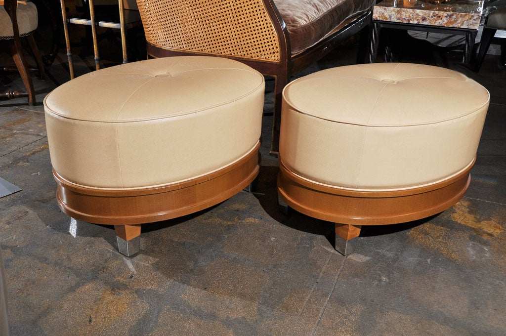 Pair of French oval ottomans with sycamore border and chrome capped tapered foot.