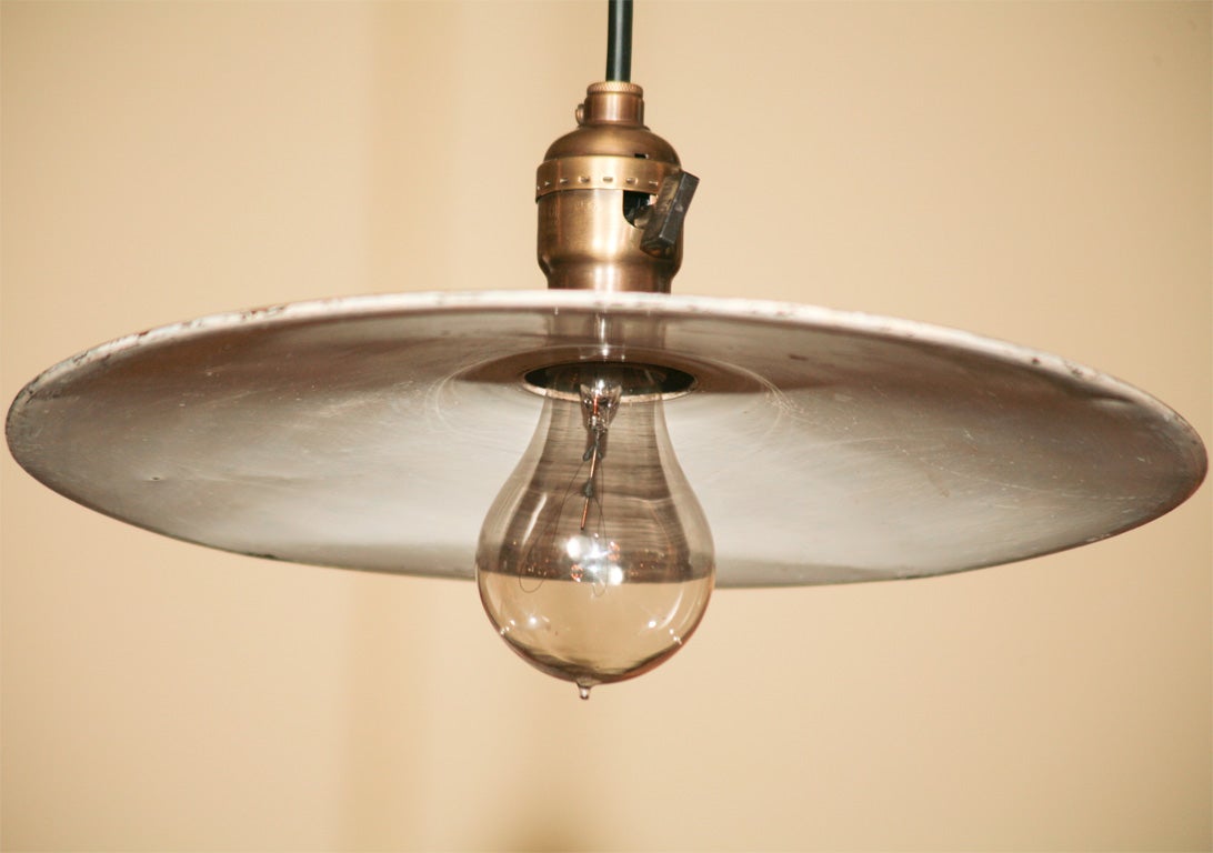 Single pendant fixture, with painted tin disc shade.  Period shade, circa 1910, with brass hardware and new rubber cording.