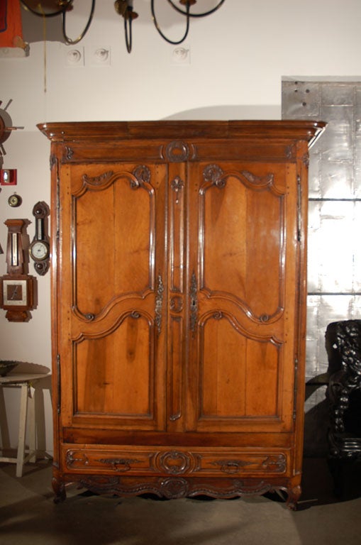 This massive French armoire, circa 1750, has paneled doors and sides, carved decorative elements, a full length drawer below and stands on small cabriole legs. The main body is 28