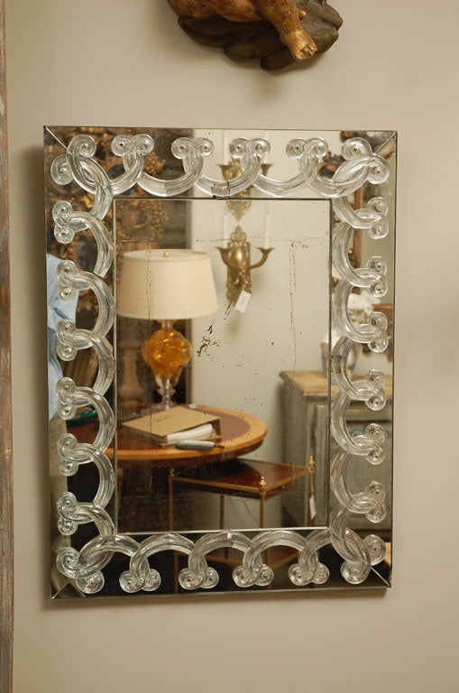 Rectangular field mirror surrounded by wide mirrored frame topped  with overlapping crystal swags.