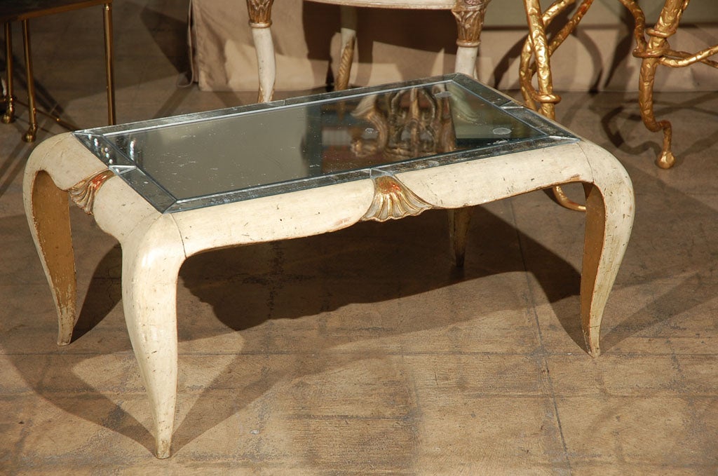 Table basse de style déco française, sculptée de façon unique, avec des détails dorés et un plateau en miroir plus récent.