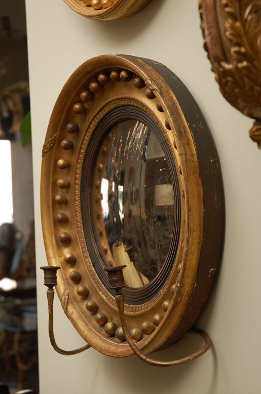 Regency Giltwood Convex Mirror.  Circular mirror plate with an ebonized reeded slip and molded ball-applied frame with candlerms to either side.