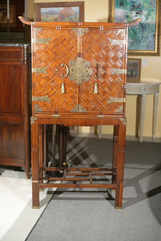 A very intriguing two-door bamboo bar cabinet, in the oriental taste, with brass decorations on stand.