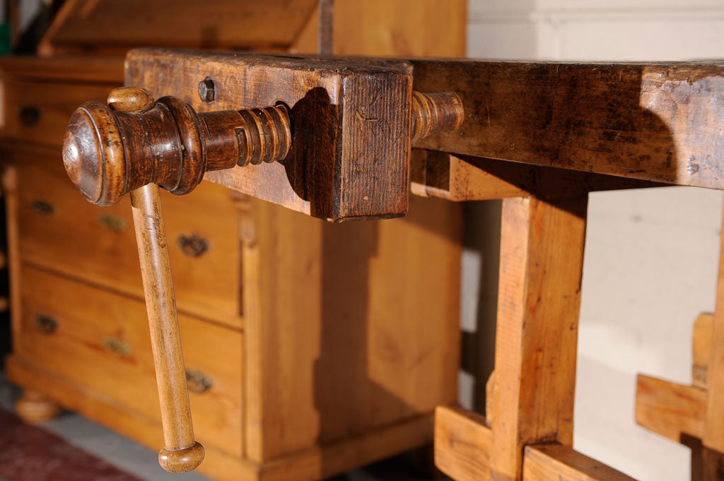 A splendid example of a 19th century carpenter's workbench featuring all original ironwork with two hand-turned vises and cleated stretcher base.