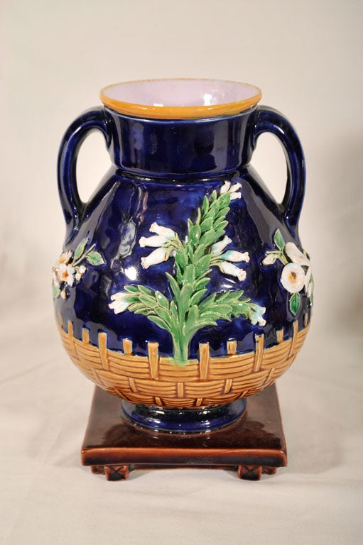 A pair of Minton Majolica vases with Lily of the Valley<br />
and other white lilies encrusted on a blue ground seemingly growing up and over a garden fence