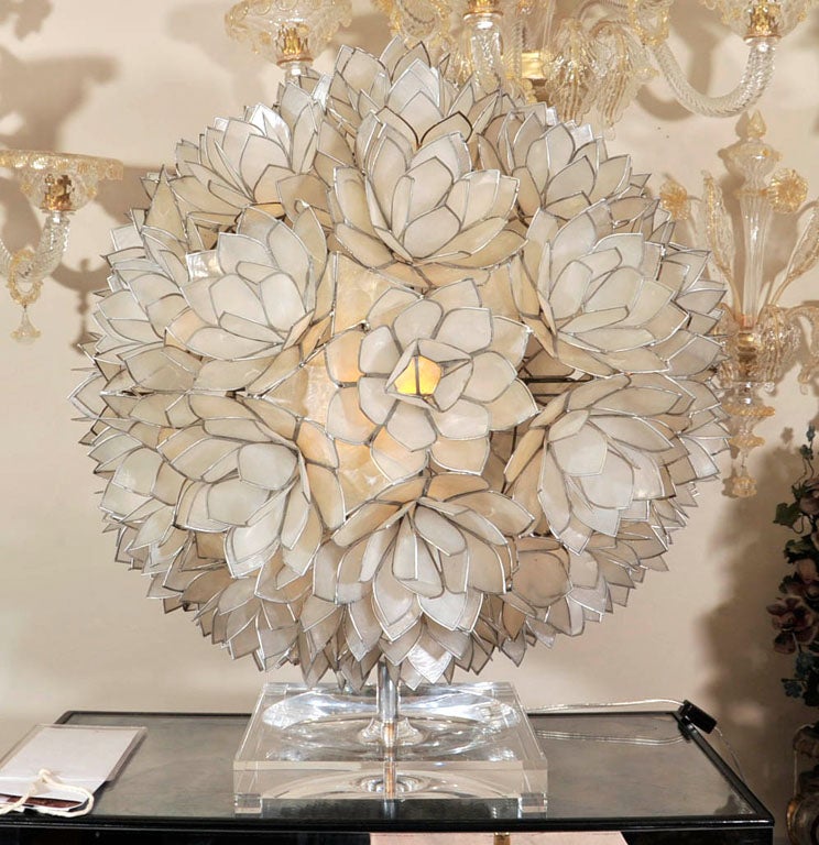 An American light in the form of an oversized round cluster of lotus flowers formed with abalone and metal edges. The interior concealing porcelain socket and secured on a rod with square lucite footed base. Circa 1970. 10