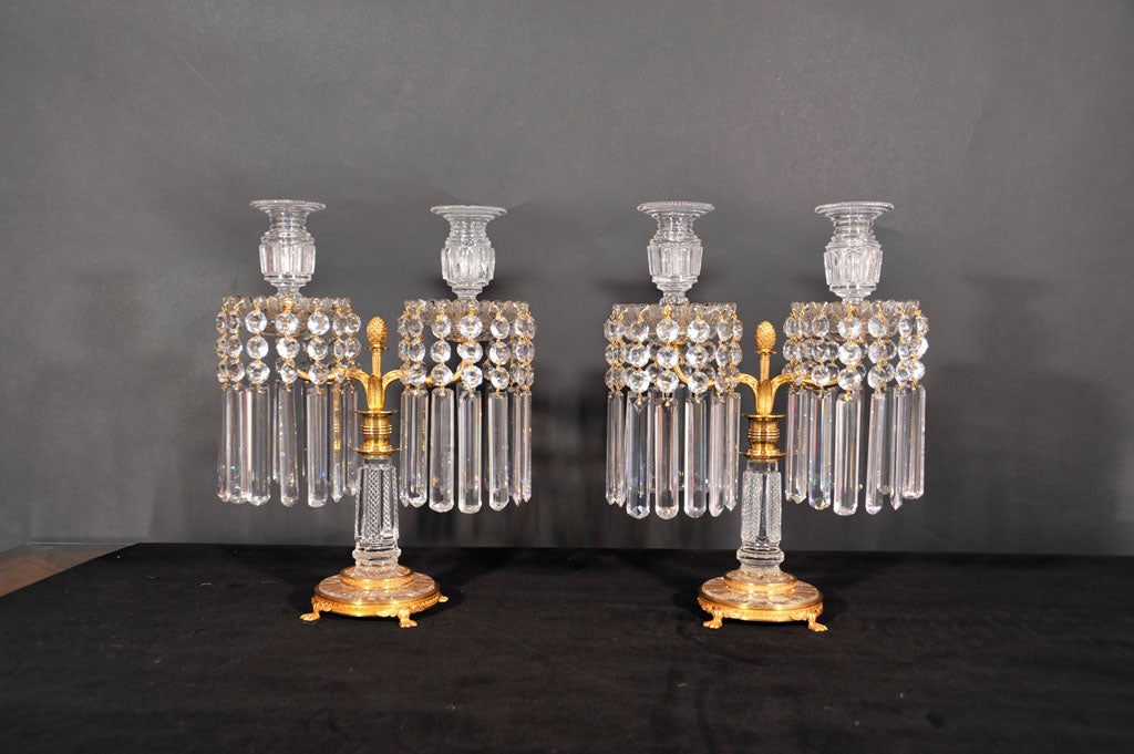 Impressive pair of English Regency cut crystal and gilt bronze mounted two light candelabra. The candle nozzles are fully cut and flair at the top with circular shaped cutting. The candelabra are supported by a fitted solid gilt bronze removal base
