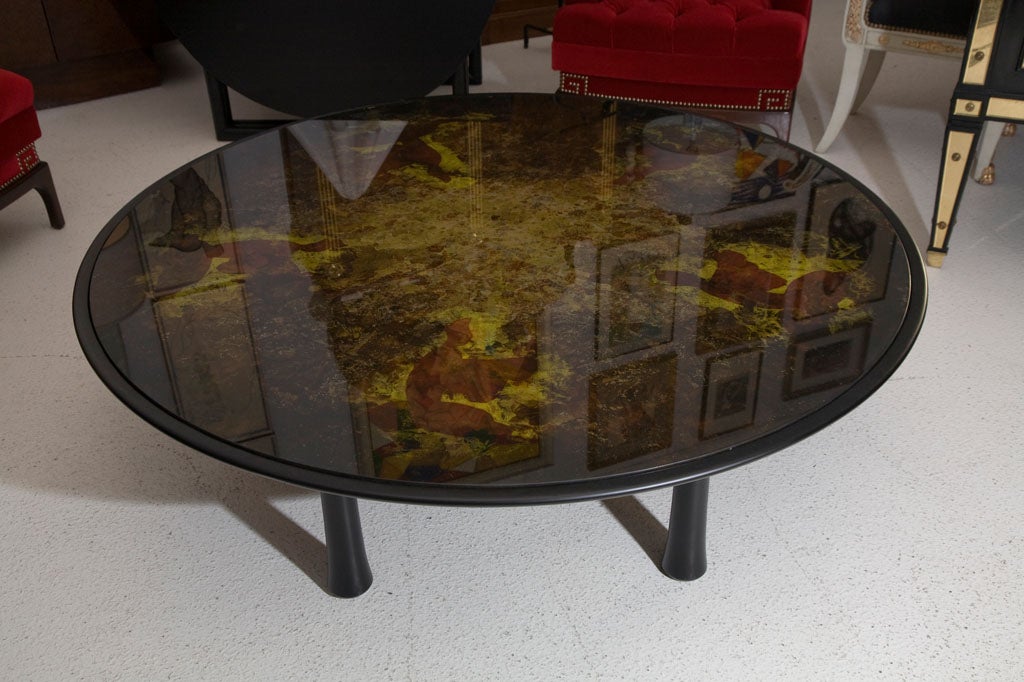 Wonderful round ebonized cocktail table with a decorated eglomise mirrored top- monumental in size.<br />
<br />
The glass top is reverse-painted in rich coppers, golds, camel, and smoke hues.  Gorgeous condition.