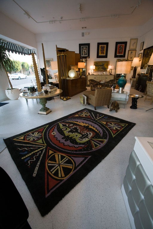 Wool rug with a colorful design on a black ground designed by French master Jean Cocteau.