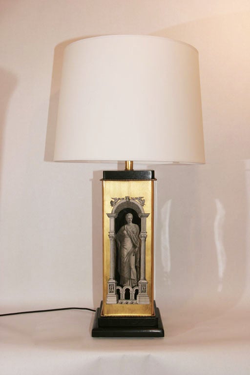 A pair of 1950s architectural form table lamps, attributed to designer Piero Fornasetti, decorated and gold leafed on the reverse side of two glass forms, with black lacquered  mounts.
Shades not included