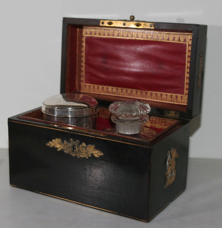 Box black English tea caddy, 19th century, England. An English black painted wooden box with bronze details and a red leather lining and with two containers for tea.