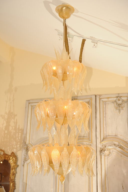 Grand Scale Hand Blown Clear Murano Glass with 14K Gold Dusted Flakes Sixteen-Light Chandelier featuring Three Graduated Concentric<br />
 Tiers of Stylized Leaves.