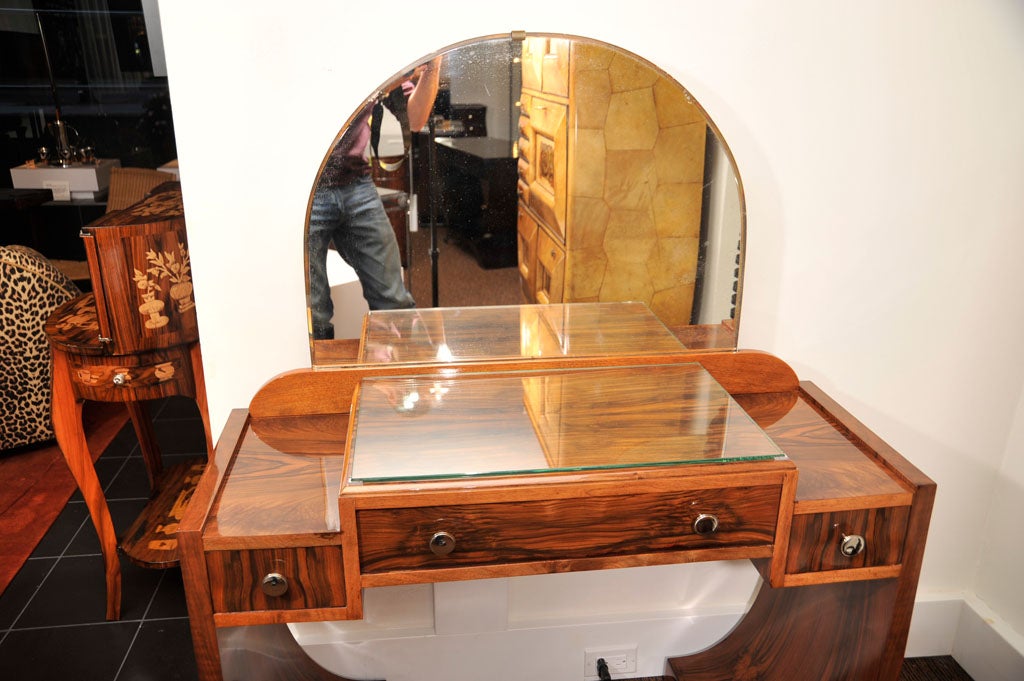 French Art Deco dressing table with exotic walnut and nickle plated hardware. There is a glass top that sits on top of the vanity; it has 1 center drawer and 2 side draws. The mirror measures 21h x 29w.