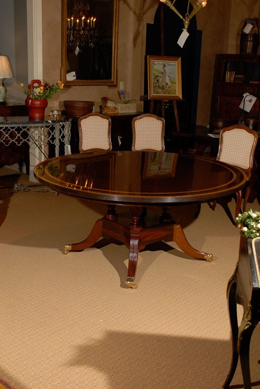 English Sheraton Mahogany round dining table with triple banded top of satinwood and rosewood.  The 1.5
