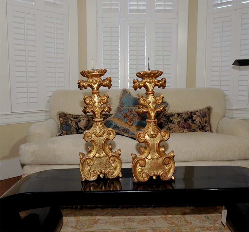 Beautifully designed and carved wooden candlesticks. Foliate and C-scroll carving. Original water gilding with some boule evident from wear. Finished on one side in part to reduce gold expense and likely use on altar.