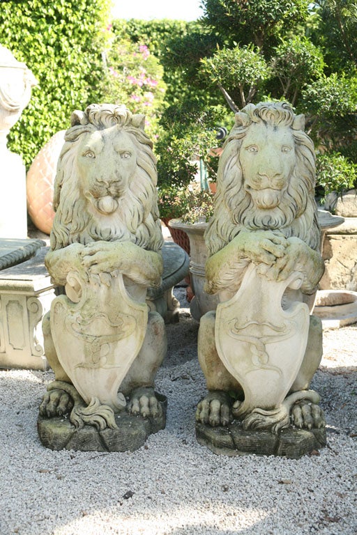 Pair of sitting lions in upright position holding family crests.