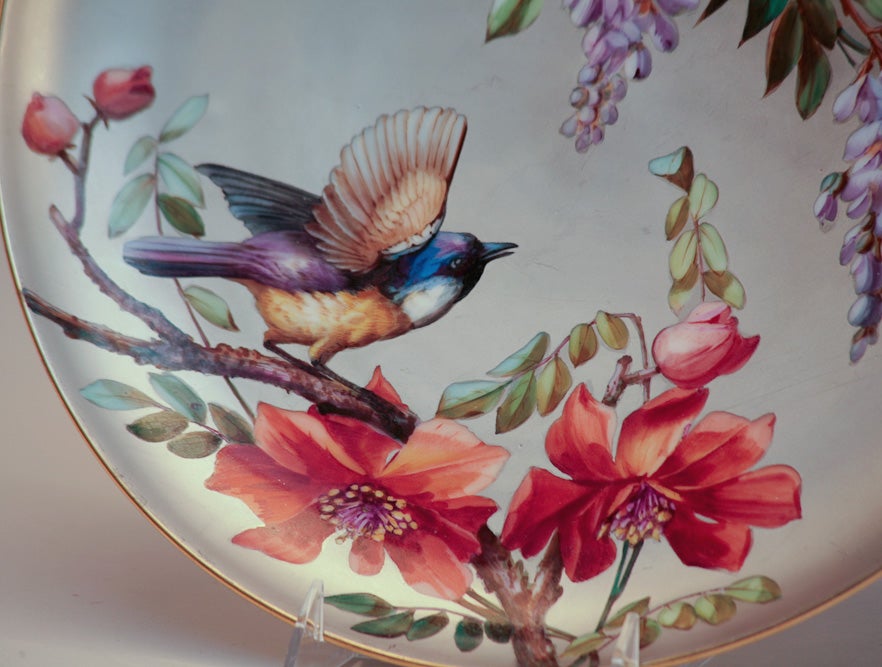 Placa de porcelana pintada a mano con decoración de esmalte policromado. Preciosos pájaros posados en ramas decoradas con flores en una pintura de esmalte de gran realismo con fondo plateado.
