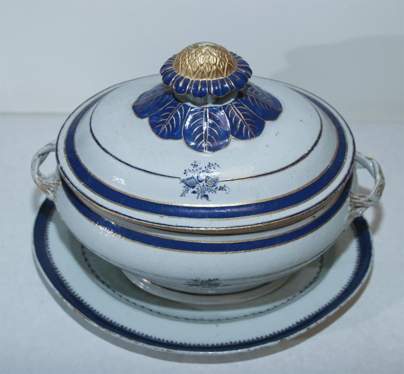 THE OVOID FORM TUREEN FITTED WITH ENTWINED BRANCH HANDLES AND FOLIATE KNOB FINIAL, DECORATED WITH FLORAL BOUQUETS. THE ASSOCIATED OVAL STAND WITH A CENTRAL INDISTINCTLY MONOGRAMMED SHIELD.<br />
DIMENSIONS:<br />
TUREEN: 11 1/2