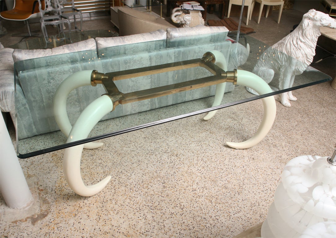 Oh-so-chic brass and faux elephant tusks dining table is a wonderful combination of the glamorous and the exotic. Solid brass frame and hardware connects four lacquered resin tusks, all topped by half-inch bevelled glass. Used as either a dining