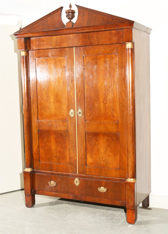 Walnut, two-door wardrobe / linen press with broken pediment crown and column sides with brass mounts. Recessed panel doors over single drawer with matching escutcheons; drawer pulls have interesting scallop backplates.